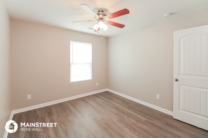 a bedroom with a ceiling fan and wood flooring