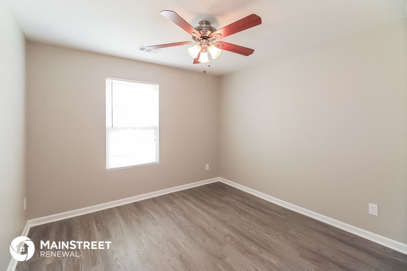 an empty room with a ceiling fan and a window