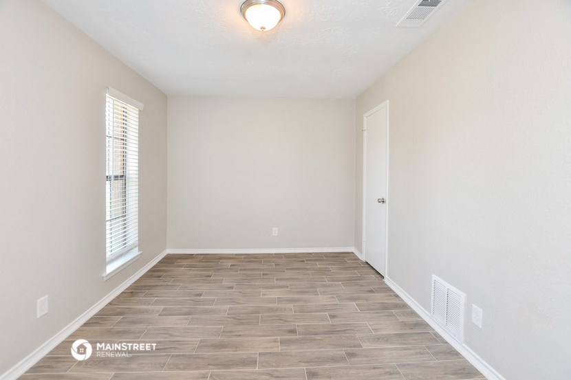 the spacious living room with wood flooring and white walls