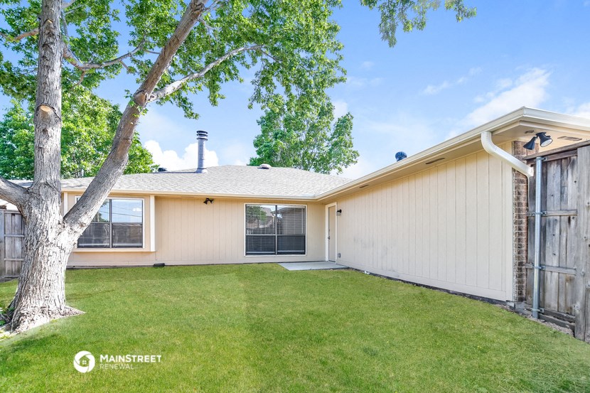 a backyard with a tree and a white house