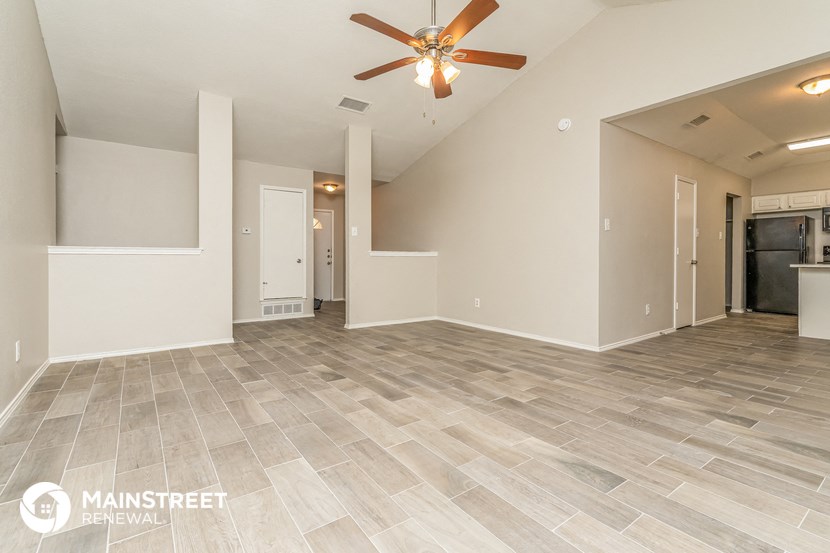 the spacious living room with tile flooring and a ceiling fan