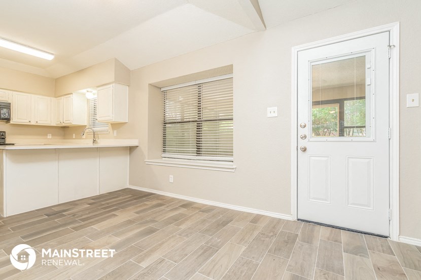 the kitchen and living room of a white house with a white door
