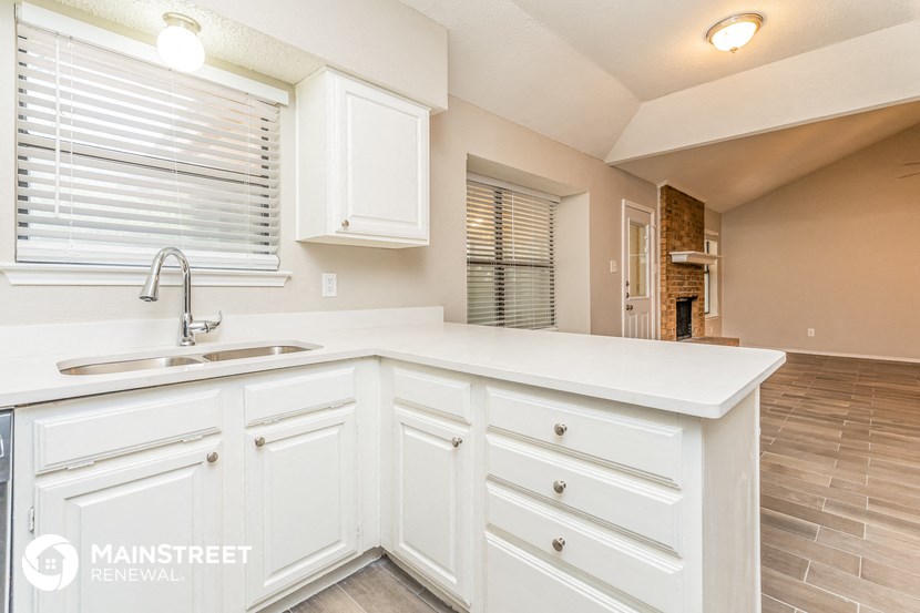 a kitchen with white cabinets and a sink and a window