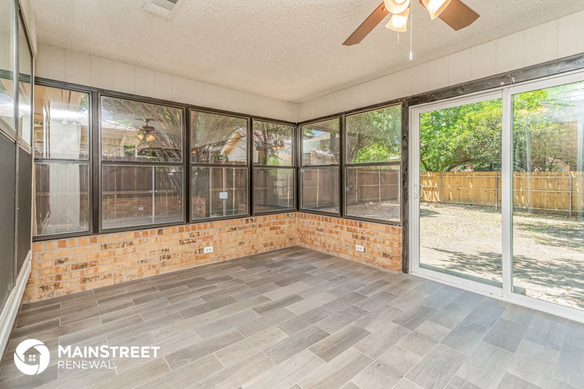 the living room of a home with large windows and a sliding glass door