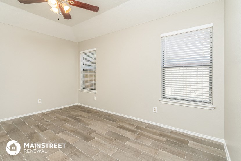 the spacious living room with tile flooring and a ceiling fan
