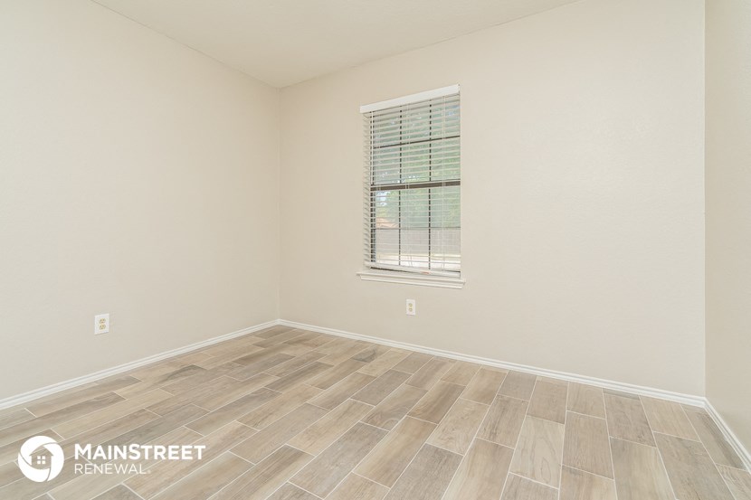 the spacious living room with wood flooring and a window