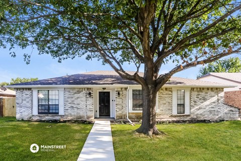 a white brick house with a tree in front of it