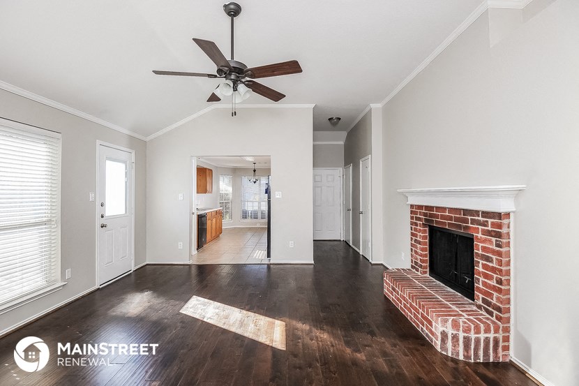 a living room with a brick fireplace and a ceiling fan