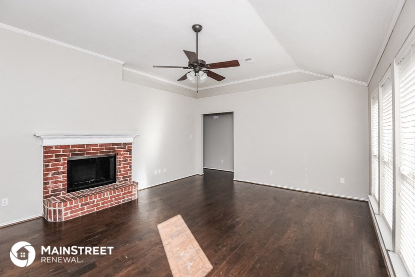 a living room with a brick fireplace and a ceiling fan