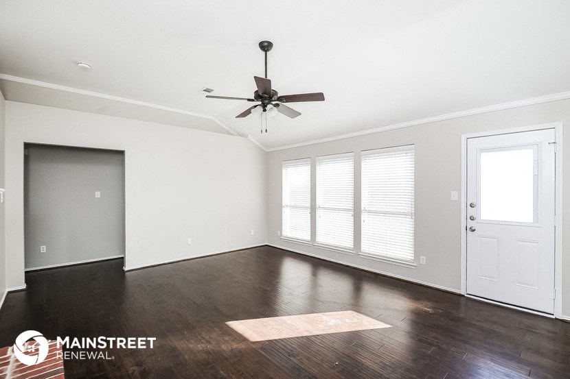 an empty living room with wood floors and a ceiling fan