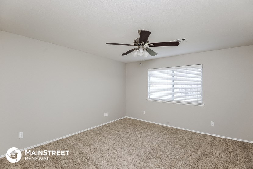 the spacious living room with ceiling fan and carpet