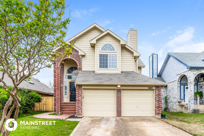 the front of a house with a garage door and a brick house