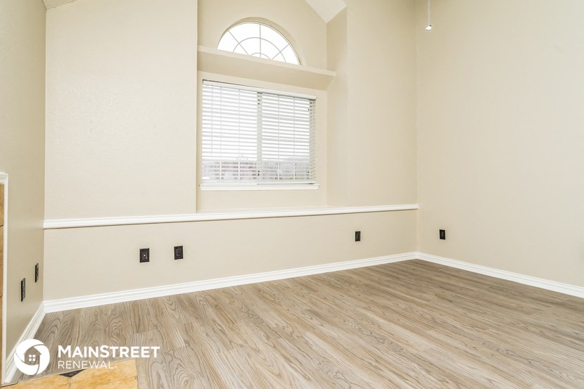 the spacious living room with a large window and wood flooring