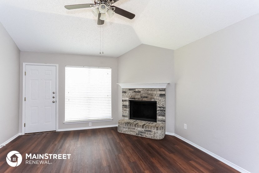 an empty living room with a fireplace and a ceiling fan