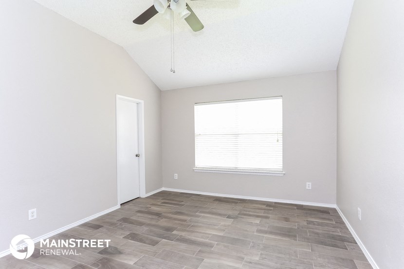 the spacious living room with a ceiling fan and a window