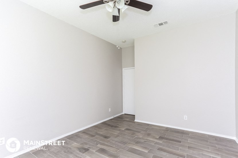 an empty room with a ceiling fan and a white wall