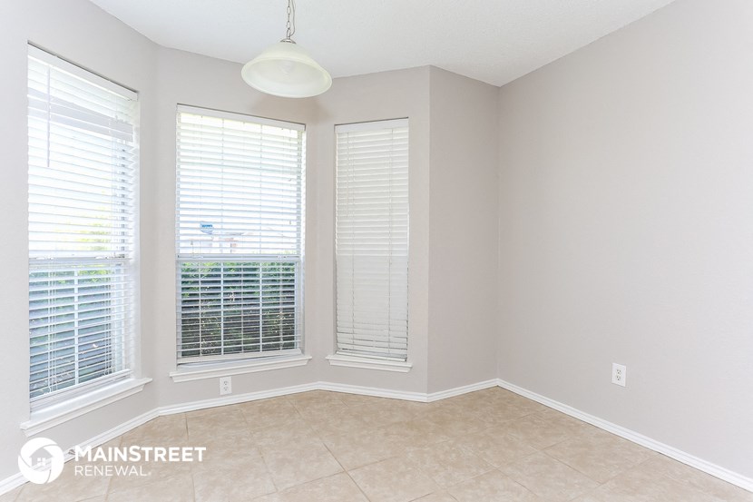 an empty living room with three windows and a tile floor
