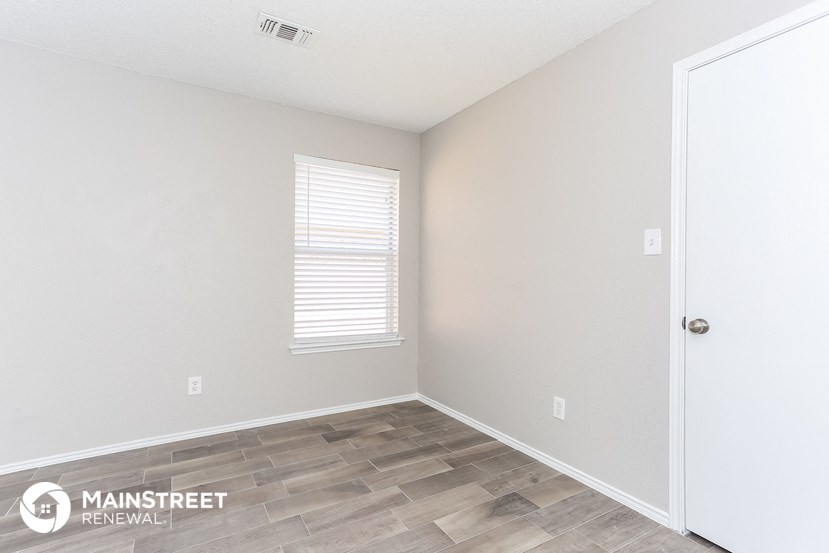 the living room of a home with a wood floor and white walls