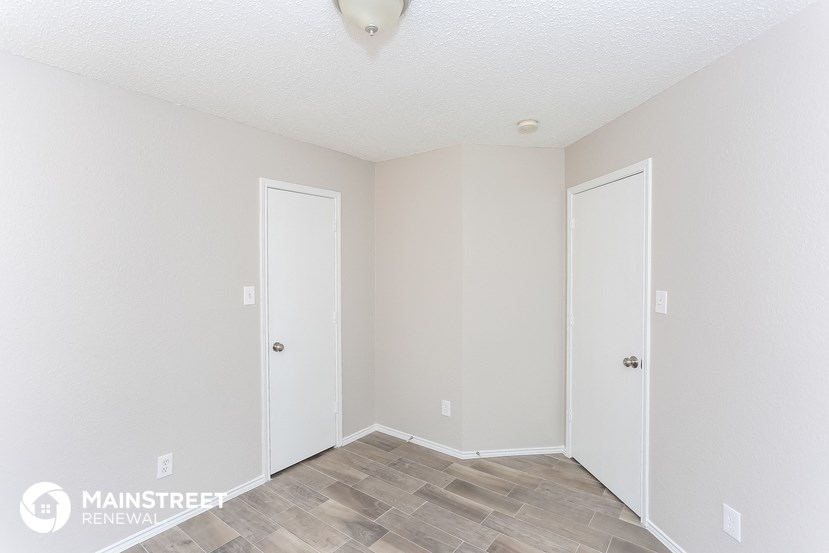 the living room of an apartment with white walls and wood flooring