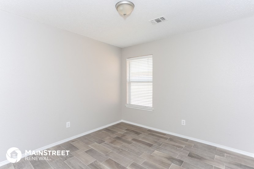 the living room of a home with a large window and wood flooring