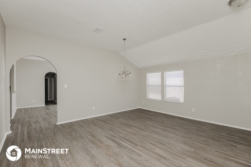 the living room and dining room of an empty house with wood flooring