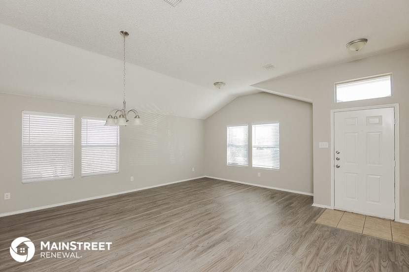 the spacious living room with wood flooring and a white door