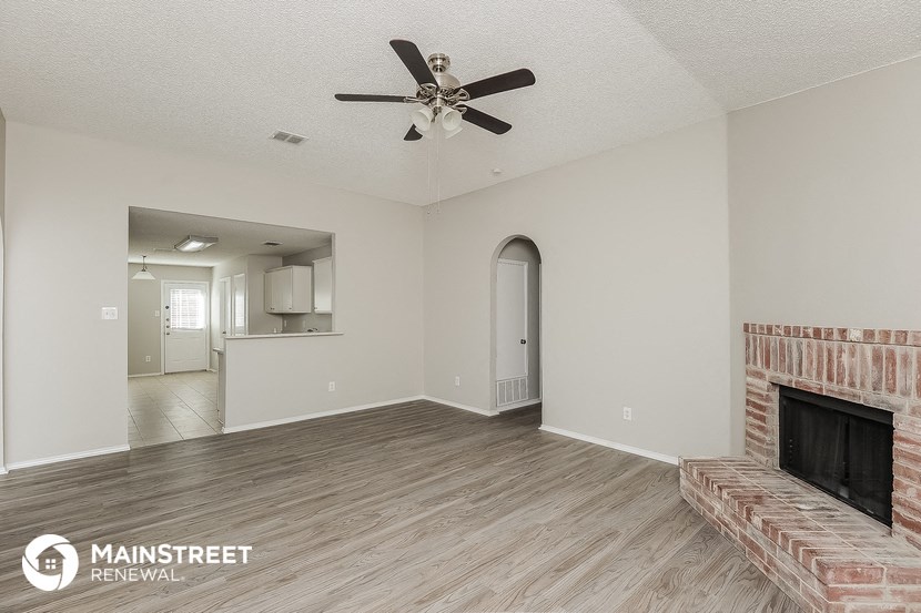 a living room with a fireplace and a ceiling fan