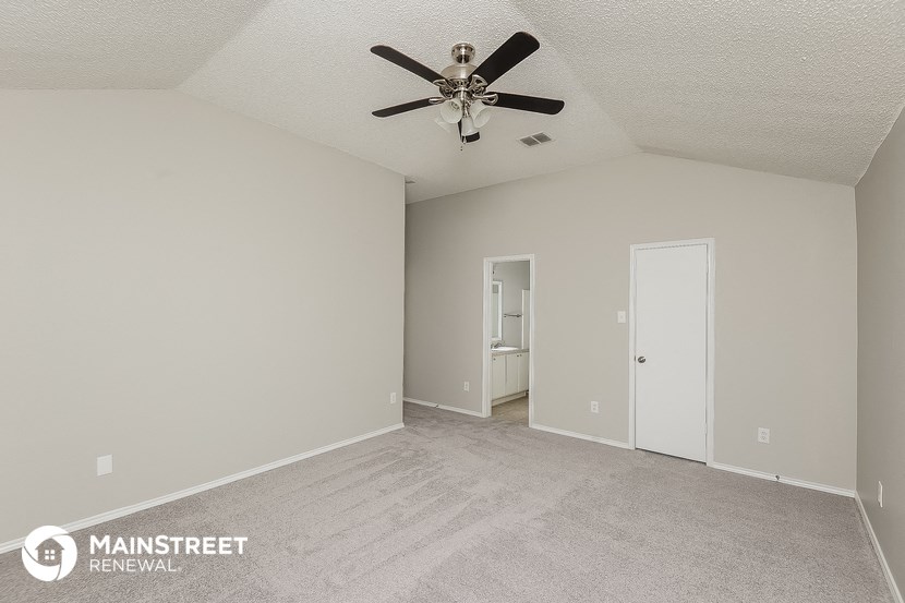the living room of an apartment with carpet and a ceiling fan