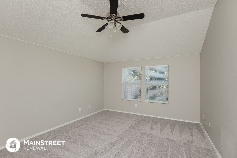 the spacious living room with ceiling fan and carpet
