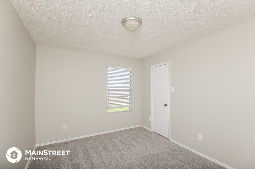 the spacious living room with carpet and a door to the bedroom