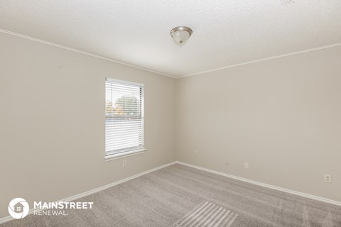 the spacious living room of a house with carpet and a window