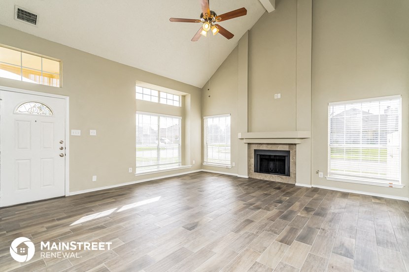 the living room with a fireplace and a ceiling fan
