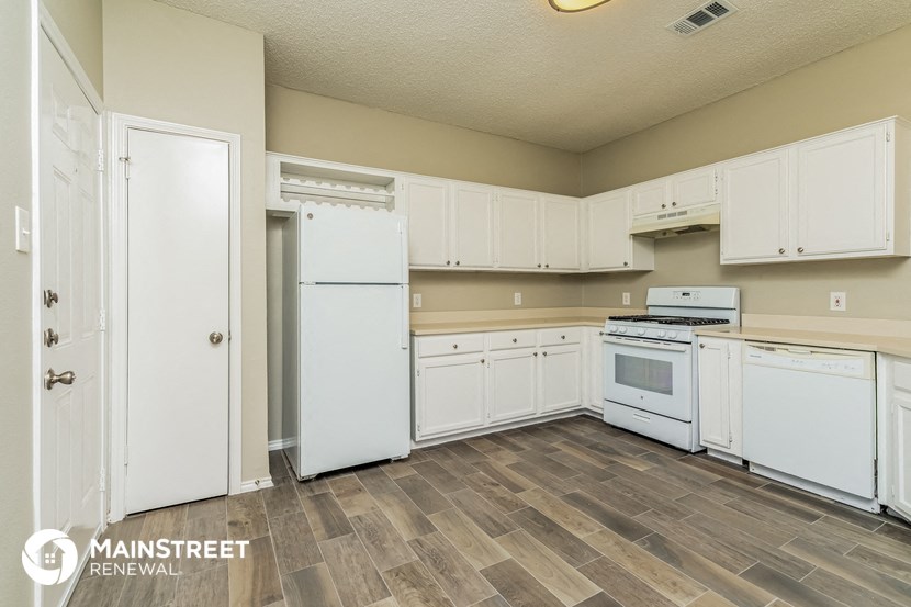 a kitchen with white appliances and white cabinets and wood flooring