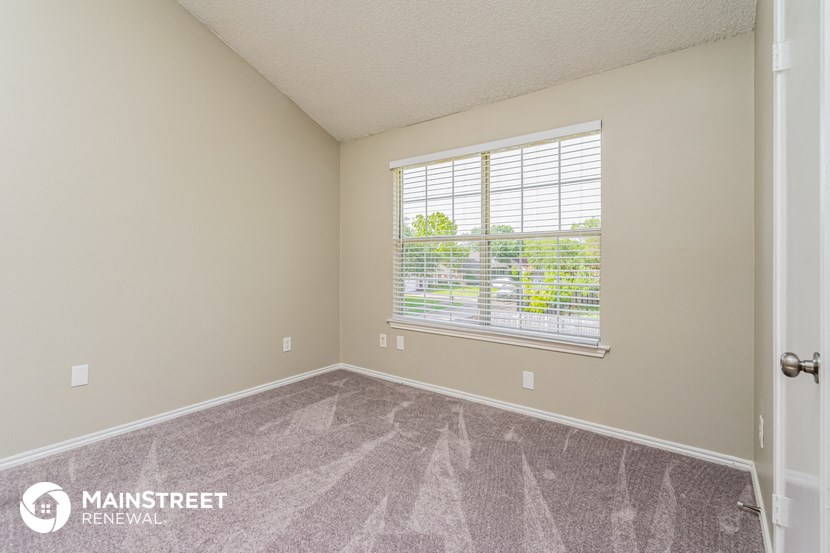 the spacious living room with a large window and carpeted flooring