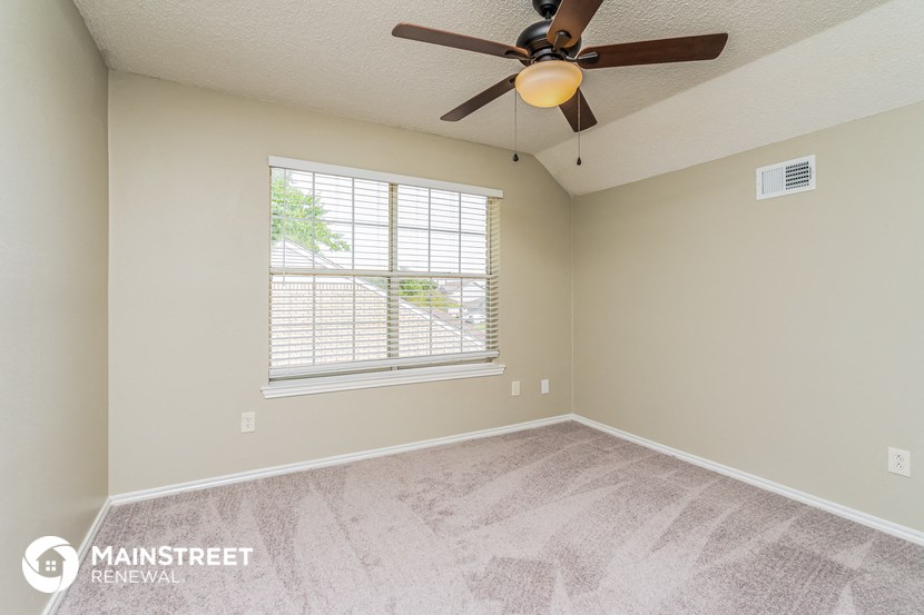 the spacious bedroom has a ceiling fan and a large window