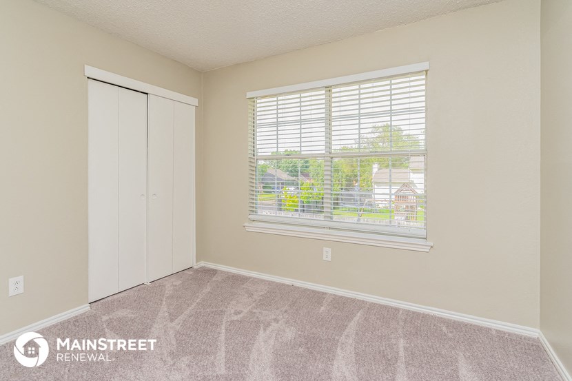 a bedroom with a large window and a closet