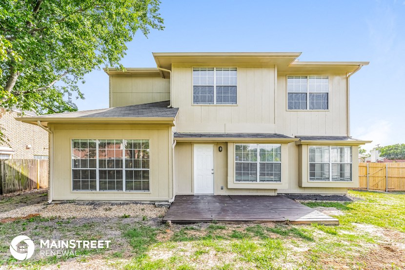 a small yellow house with a wooden deck in front of it