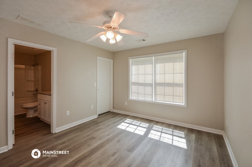 an empty living room with a ceiling fan and a window