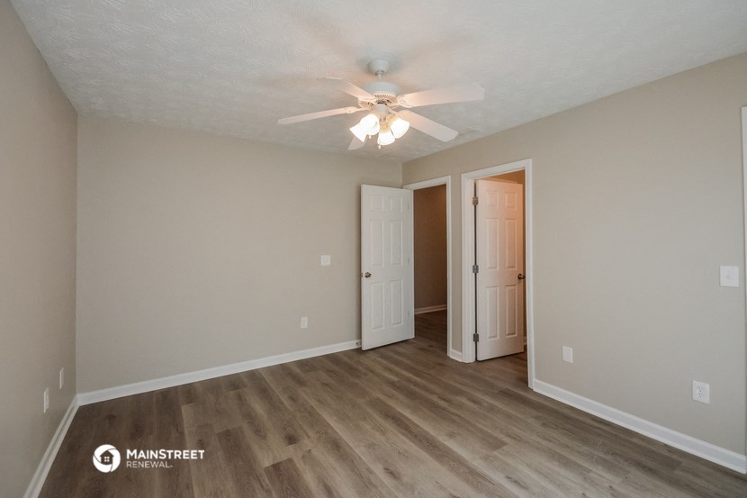 the spacious living room with ceiling fan and wood flooring