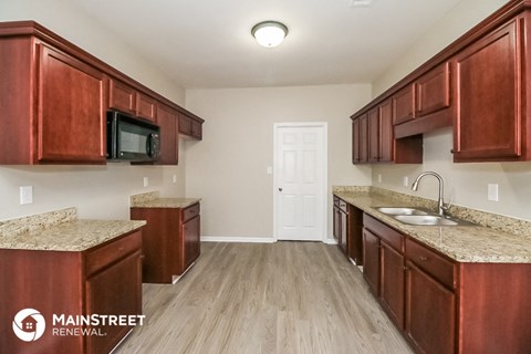 a kitchen with wooden cabinets and granite counter tops and a sink and a microwave