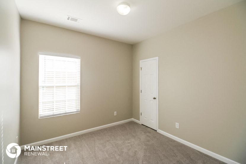 a bedroom with beige walls and a white door and a window