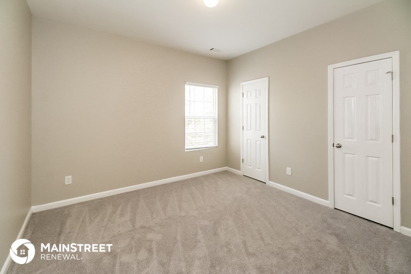 the spacious living room with carpeted flooring and two doors
