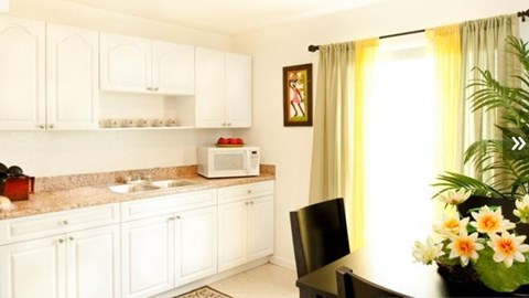 A kitchen with white cabinets and a black chair.