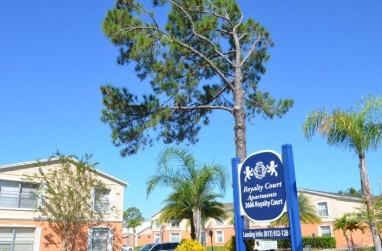 a tree in front of a building with a blue sign