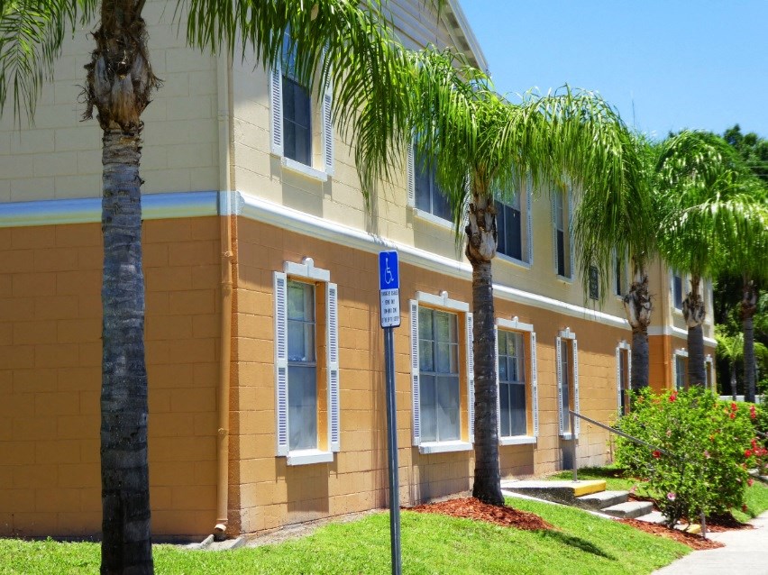 a yellow building with two palm trees in front of it
