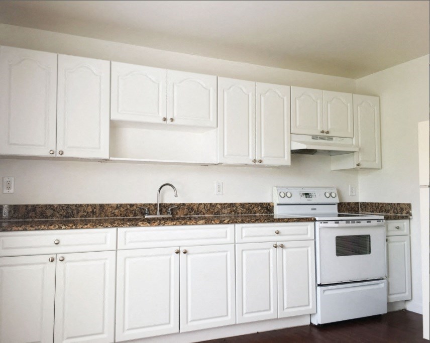 a kitchen with white cabinets and white appliances and granite counter tops