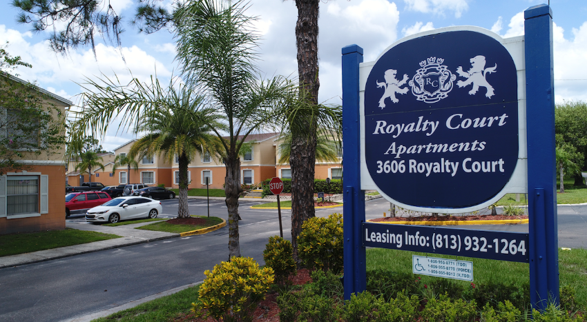 a sign for royally court apartments in front of a parking lot