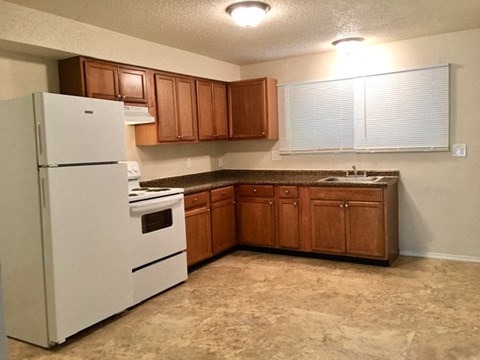 A kitchen with a white refrigerator, brown cabinets, and a brown countertop.