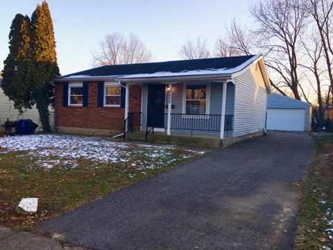 a small brick house with a porch and a driveway