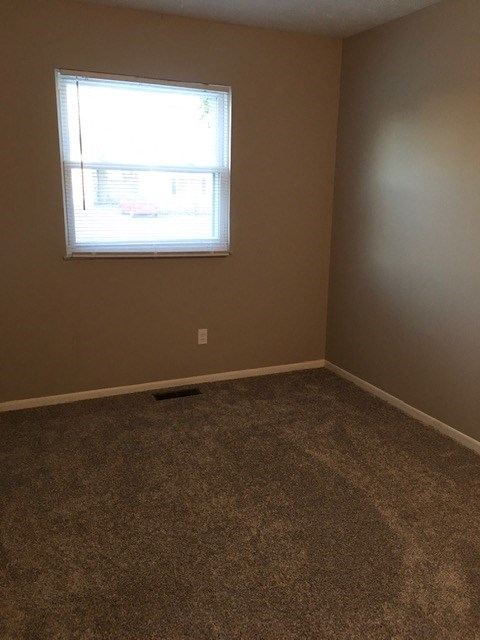 an empty room with a window and a carpet